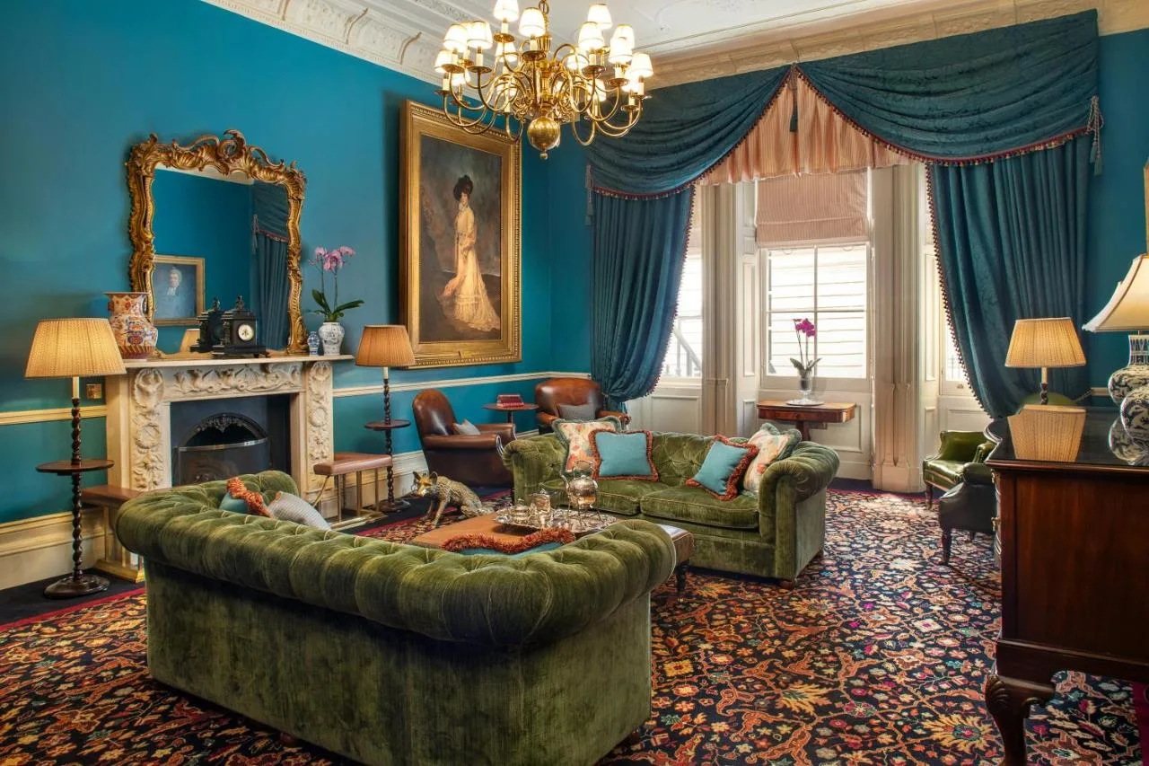 Blue-walled lounge with green sofa at The Gore London